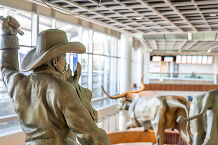 Dallas, Texas, US - 10.2022 - Statue of a cowboy running cattle in the DFW airport rental car facilityのeditorial素材