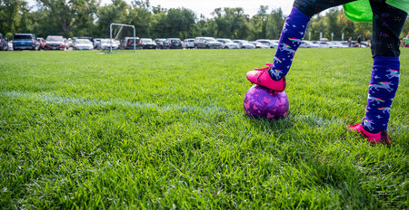 Selective focus on girls soccer ball with a player on the grass field.の写真素材