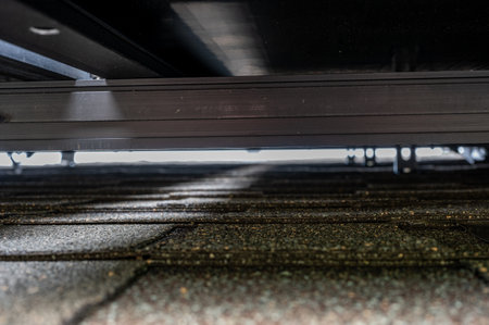 Gap underneath solar panels and asphalt shingle roof with rails and anchors visible.