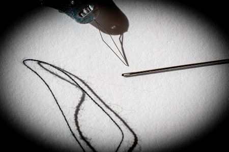 Sewing needle threader tool in use and a single black string.の写真素材