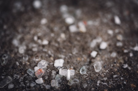 macro ground level closeup view of rock salt ice-melt on concrete with a frozen layer.の写真素材