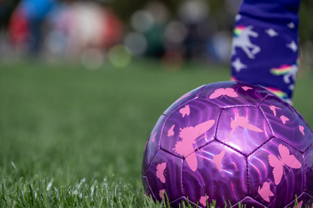 Selective focus on girls soccer ball with a player on the grass field.の写真素材