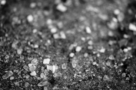 macro ground level closeup view of rock salt ice-melt on concrete with a frozen layer.の写真素材