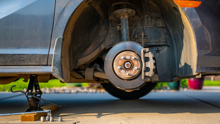 Wheel well of a vehicle lifted with a tire jack. Rusted hub and strut visible.の写真素材