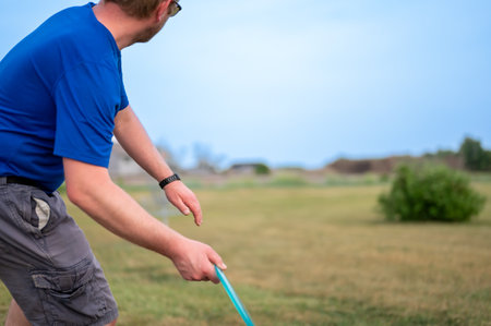 Selective focus on a Caucasian adult preparing to sidearm throw a disc golf towards the pin.の写真素材