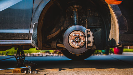 Wheel well of a vehicle lifted with a tire jack. Rusted hub and strut visible.の写真素材