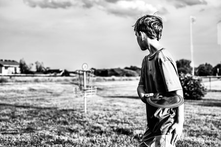 Young Caucasian male boy aiming a disc golf at a chain goal.の写真素材