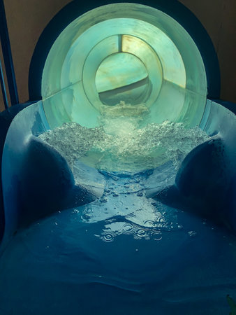 Entrance of a waterslide tube with rushing water.