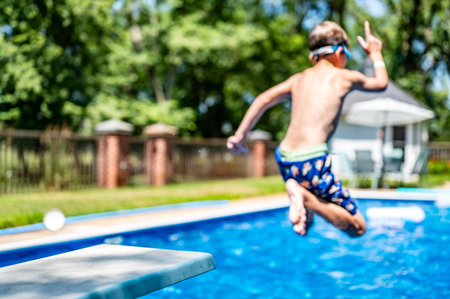 Selective focus on a swimming board as a young boy jumps into a pool.の写真素材