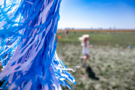 Selective focus on a pom-pom streamer with defocused child running in the backgroundの写真素材