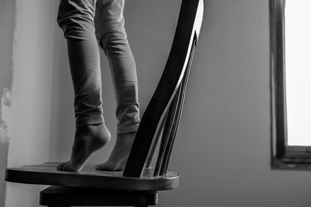 Young girl on a chair reaching high to paint a wall