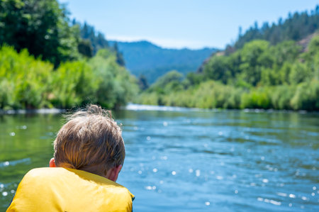 Selective focus on a child rafting down the wild and scenic Rogue River while wearing a life jacketの写真素材