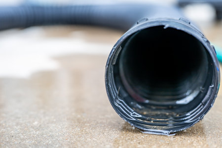 Selective focus on the front opening of a residential sump pump discharging water from the end of a...