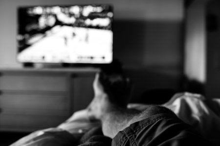 Selective focus on propped up feet with a blurred basketball game on the TV
