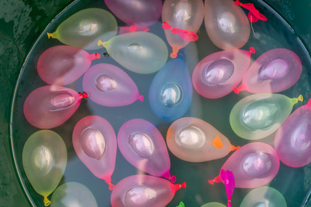Collection of multicolored water balloons in a bucket.の写真素材