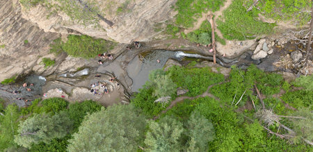 Drone view above people sliding in the Devils Bathtub waterfall and pool in Spearfish Canyon, South...
