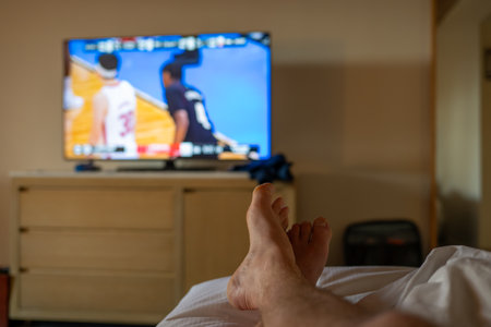 Selective focus on propped up feet with a blurred basketball game on the TVの写真素材