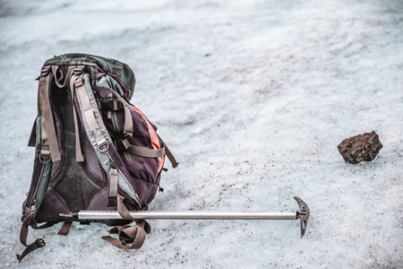 Outdoor hiking backpack and pick sitting on compacted snow and ice of a glacierの写真素材