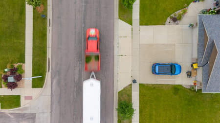 Aerial view from above of a SUV parked in a driveway backing out while another vehicle drives byの写真素材