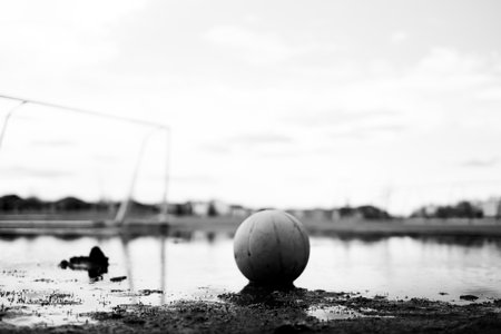 Selective focus on mud in front of a ball sitting in a mudpuddle of water at a school playground.の写真素材
