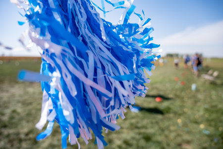 Selective focus on a pom-pom streamer with defocused child running in the backgroundの写真素材