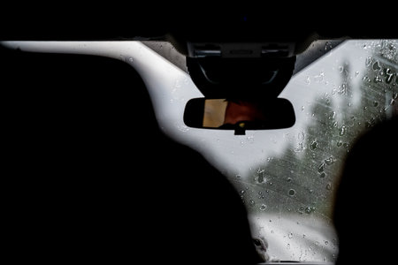Obstructed view from the back seat of a vehicle with rain falling on the front window.の写真素材