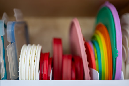 Narrow depth of field picture of an open kitchen cabinet with rows of organized storage of plastic lids.の写真素材