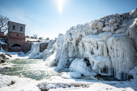 Sioux Falls Park waterfall with ice and snow. Cascading snowmelt water pouring over the top into a pool of standing water.の写真素材
