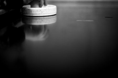 Selective focus on an air hockey table and a small child holding the paddle.の写真素材