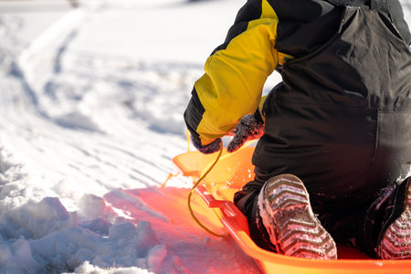 Selective focus on the snow boot of a child going down a hill on a sledの写真素材
