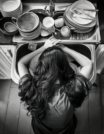 Overwhelmed person resting on kitchen sink filled with dirty dishes at home during afternoon Generative AIの素材