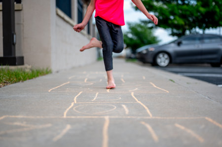 Selective focus on chalk numbers with a girl playing hop-scotch barefootの写真素材