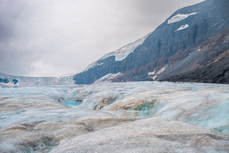 Crevasse in the ice from melting at Athabasca Glacier in Jasper National Park with cloudy skyの写真素材