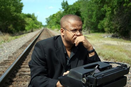 Young man with his typewriter on the train tracks.の写真素材