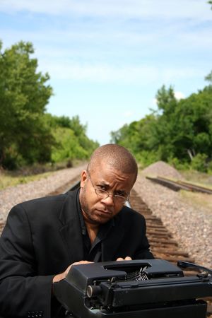 Young man with his typewriter on the train tracks.の写真素材
