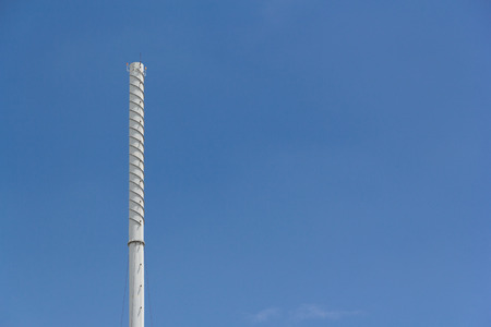 white factory chimney with electrical detector on the top of stack