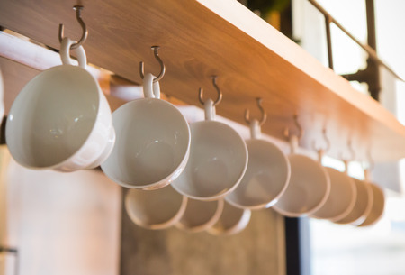 white coffee cups hang on the wooden  panelの写真素材