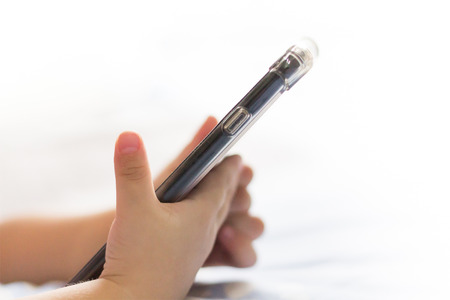 kid hand hold mobile phone on white backgroundの写真素材