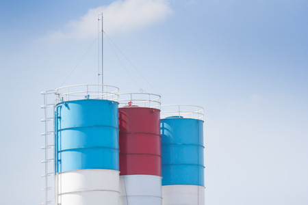blue and red steel silo against blue sky, metal silos for concrete mix process plant.の写真素材