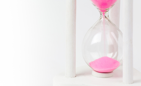 pink sand in hourglass on white background