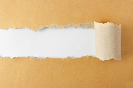 Brown package paper torn to reveal white panel ideal for copy spaceの写真素材