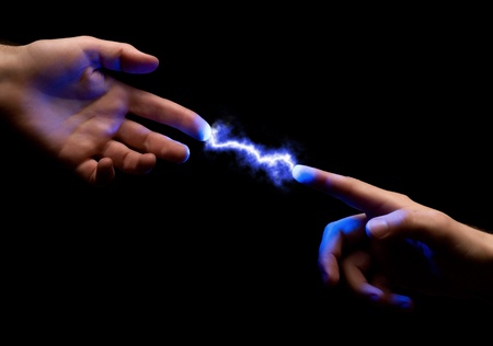 blue powerful electric spark between two fingers of mans hands on black backgroundの写真素材