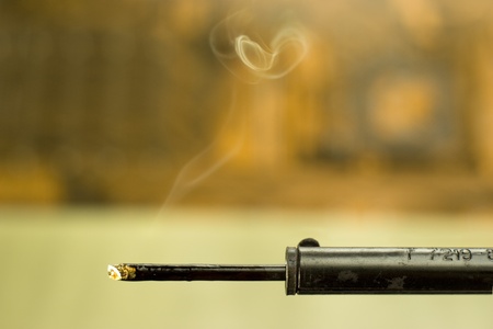 closeup of heated soldering iron with smoke on blurred backgroundの写真素材