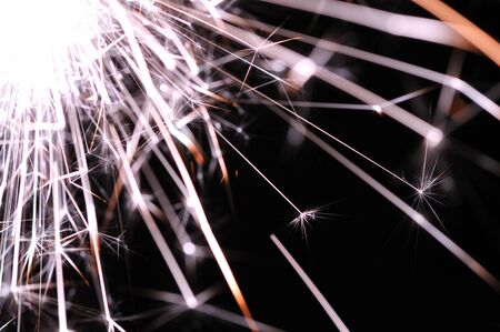 Close-up of golden sparkles of a burning fire on a black background in honor of the holiday. Happy New Year and Christmas and Happy Birthday greetings conceptの写真素材