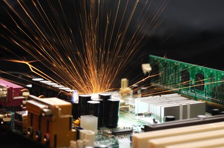 Bright burning sparks fly from the chip of complex electronic equipment. Factory breakdown concept. Breakdown of a new microcircuitの写真素材