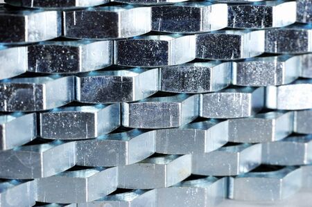 Close-up wall of numerous chrome metal nuts in the form of honeycombs next to each other. Background concept for the theme of repairing fasteners and small manufacturing partsの写真素材