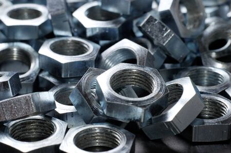 Side view close-up chrome metal nuts in the shape of honeycombs lie next to each other forming an area. The concept of fasteners and construction. Repair and parts conceptの写真素材