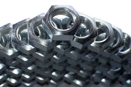 Close-up wall of numerous chrome metal nuts in the form of honeycombs next to each other. Background...