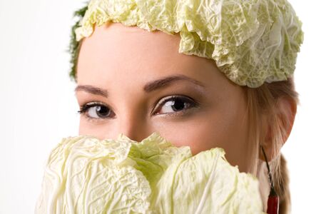 Portrait of european woman posing with peppers and cabbage leaf on head. Red and green spices used...