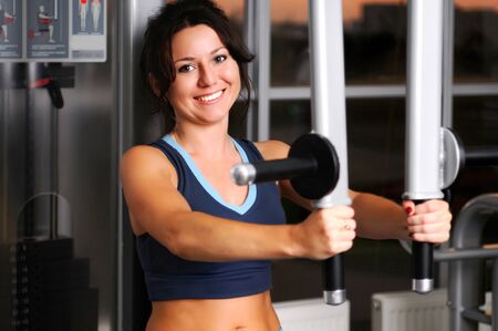 Training caucasian white brunette woman doing exercise for arm muscles on fitness equipment with...